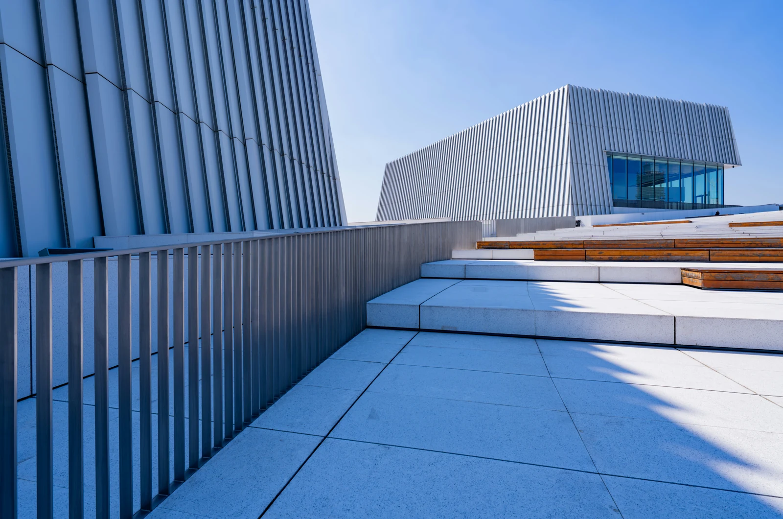 A blue structural façade rising in connected terraces